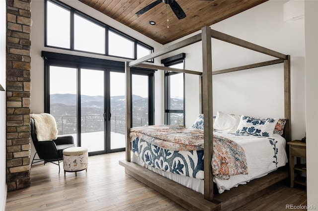 bedroom with ceiling fan, access to outside, multiple windows, wooden ceiling, and a mountain view