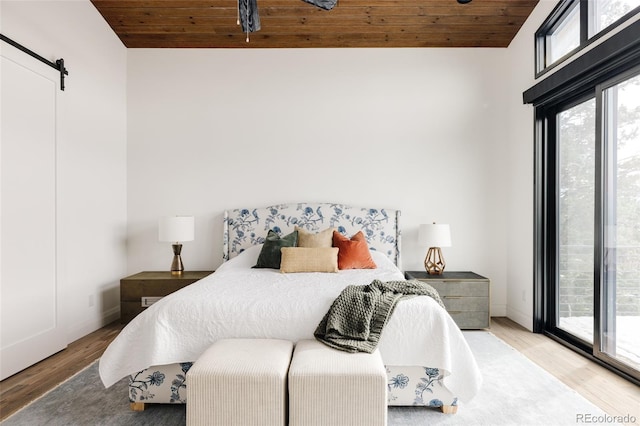 bedroom featuring access to exterior, a barn door, wooden ceiling, and hardwood / wood-style flooring