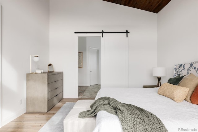 bedroom with wood ceiling, light wood-type flooring, a barn door, and lofted ceiling