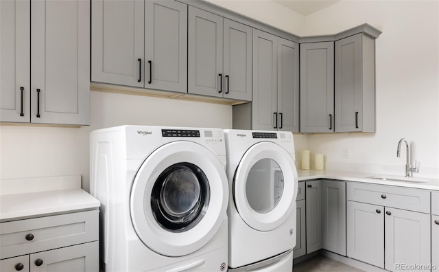 clothes washing area featuring cabinets, sink, and washer and clothes dryer