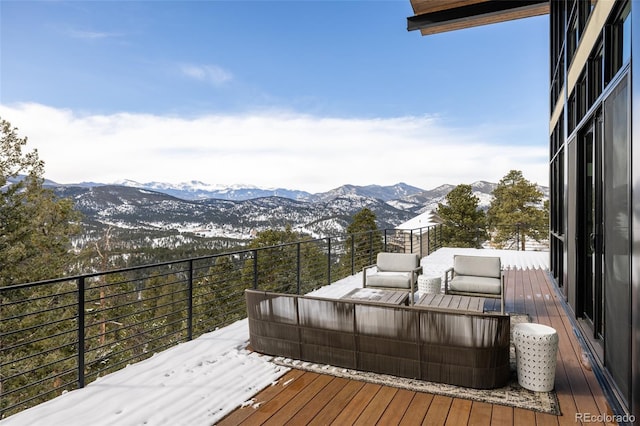 snow covered deck featuring a mountain view and an outdoor hangout area