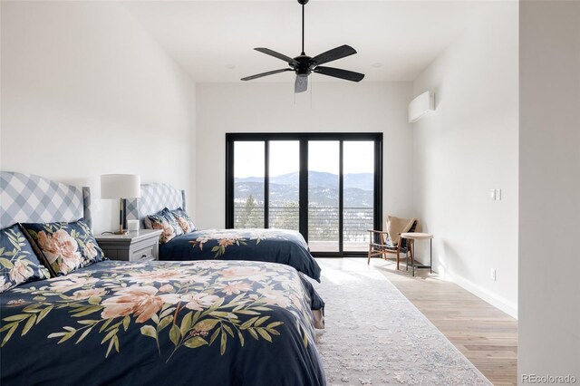 bedroom featuring a mountain view, light hardwood / wood-style floors, ceiling fan, and access to outside