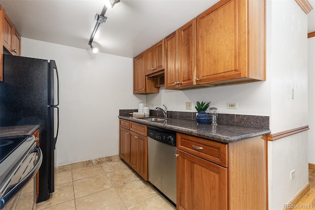 kitchen featuring sink, rail lighting, dark stone countertops, light tile patterned floors, and appliances with stainless steel finishes