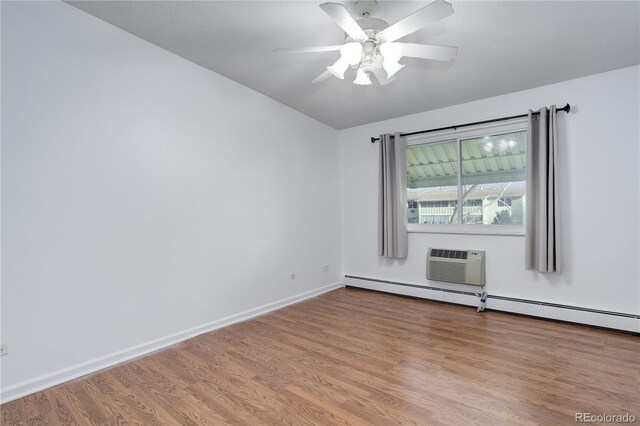 empty room featuring wood finished floors, baseboard heating, a ceiling fan, a wall mounted air conditioner, and baseboards