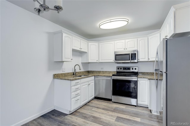 kitchen with stainless steel appliances, a sink, light wood-type flooring, and white cabinets