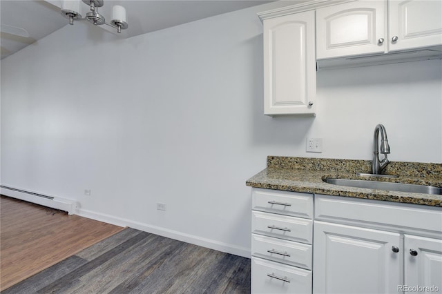 kitchen with a baseboard radiator, a sink, dark wood finished floors, dark stone countertops, and white cabinetry