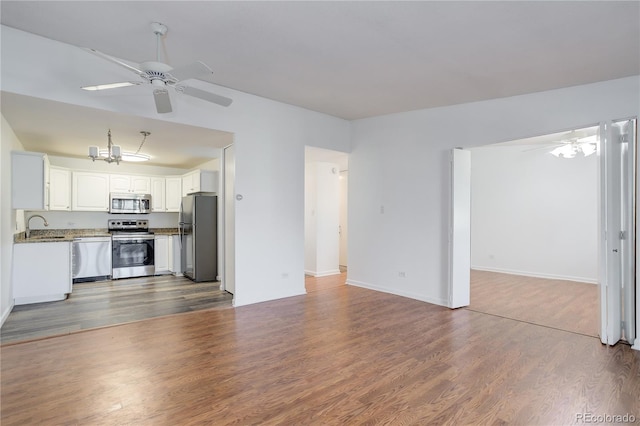 unfurnished living room with a ceiling fan, a sink, dark wood-type flooring, lofted ceiling, and baseboards