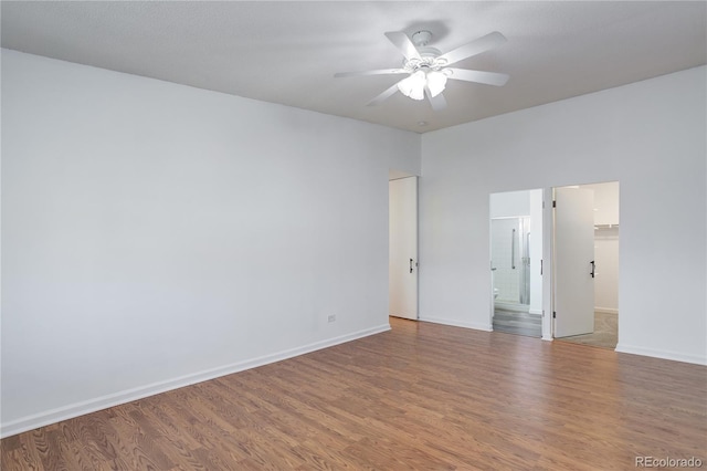 empty room featuring wood finished floors, a ceiling fan, and baseboards