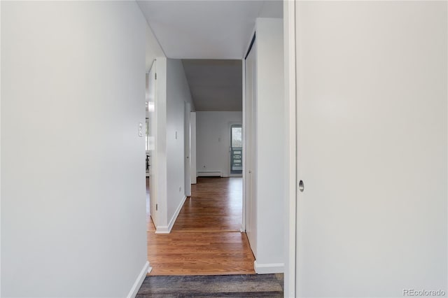 corridor featuring a baseboard radiator, wood finished floors, and baseboards