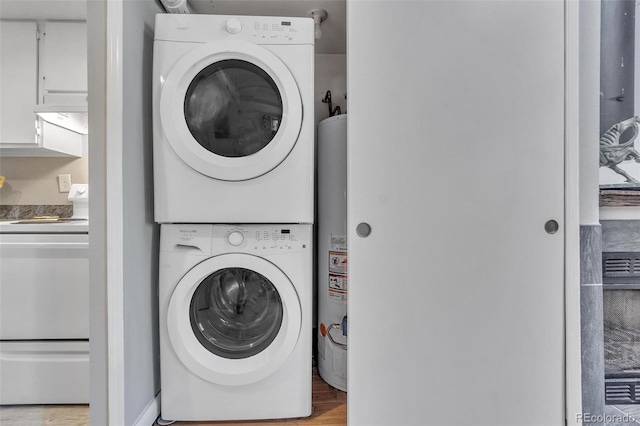 laundry area with light wood-type flooring, stacked washer and dryer, and water heater