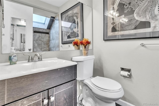 bathroom with a skylight, vanity, and toilet