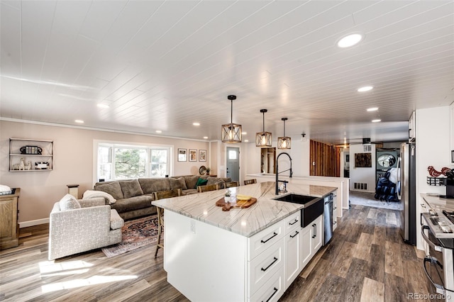 kitchen with dark wood-style floors, appliances with stainless steel finishes, light stone countertops, and a sink