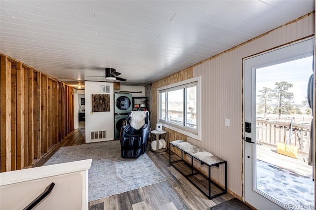 sitting room featuring stacked washer / dryer, wood finished floors, visible vents, and wood walls