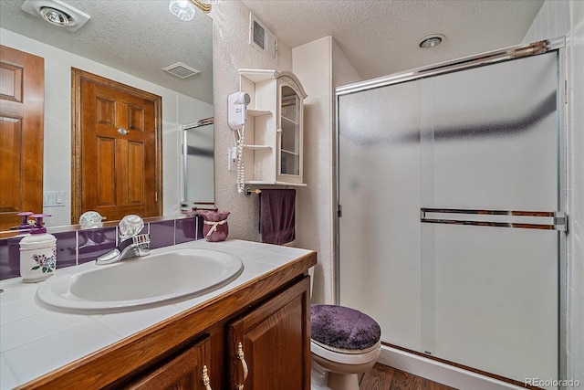 bathroom with toilet, an enclosed shower, wood-type flooring, a textured ceiling, and vanity