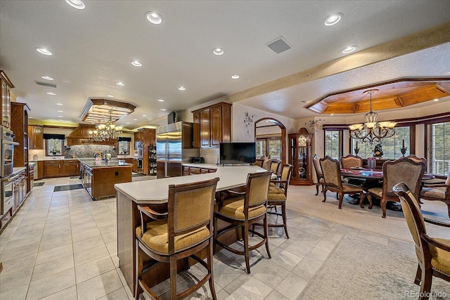 tiled dining room with a notable chandelier, a tray ceiling, and a wealth of natural light