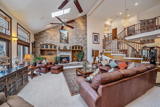 living room featuring a skylight, carpet flooring, high vaulted ceiling, ceiling fan with notable chandelier, and a stone fireplace