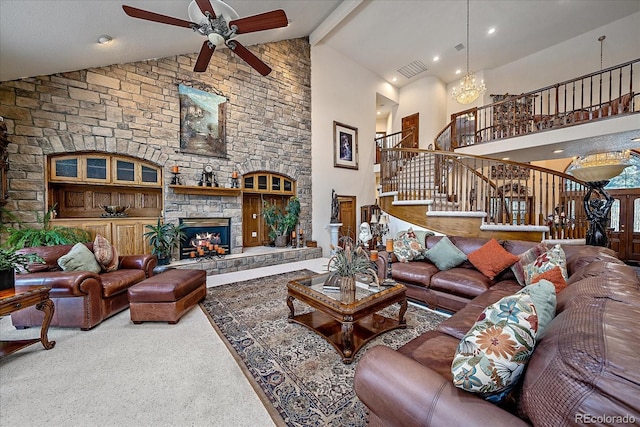 living room with carpet, beamed ceiling, a fireplace, high vaulted ceiling, and ceiling fan with notable chandelier