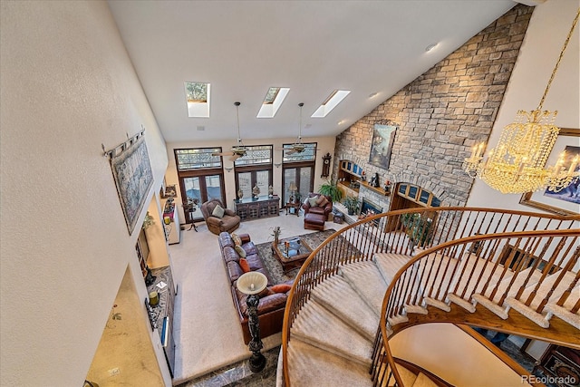 carpeted living room with an inviting chandelier, high vaulted ceiling, and a skylight