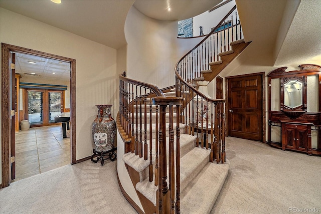 stairs featuring light carpet and french doors