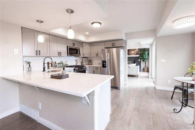 1772 Eisenhower, Louisville, CO 80027 - kitchen featuring stainless steel appliances, gray cabinetry, light countertops, a peninsula, and light wood-style flooring