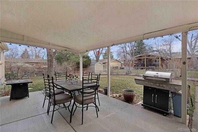 view of patio / terrace with an outbuilding, fence, area for grilling, outdoor dining area, and a storage unit