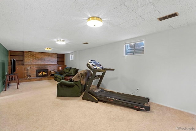 workout room with a fireplace, carpet, visible vents, and baseboards