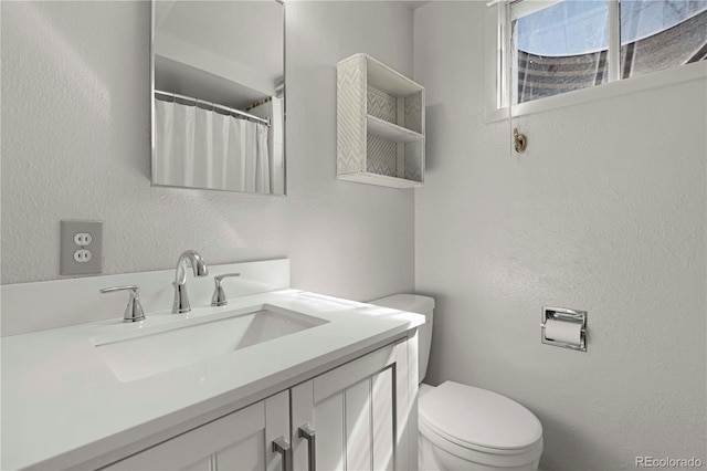 bathroom featuring a shower with curtain, toilet, vanity, and a textured wall