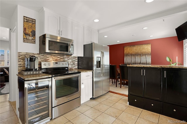 kitchen with light stone countertops, wine cooler, white cabinets, appliances with stainless steel finishes, and backsplash