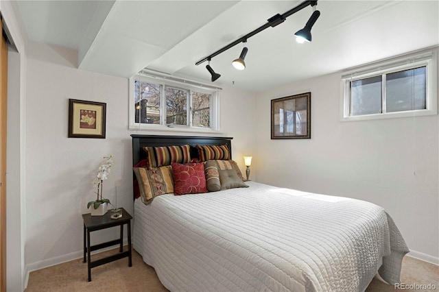 carpeted bedroom featuring multiple windows, baseboards, and track lighting