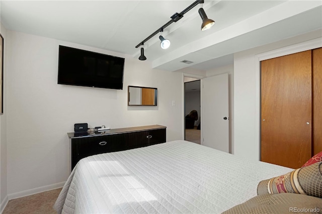 bedroom featuring track lighting, carpet flooring, baseboards, and a closet