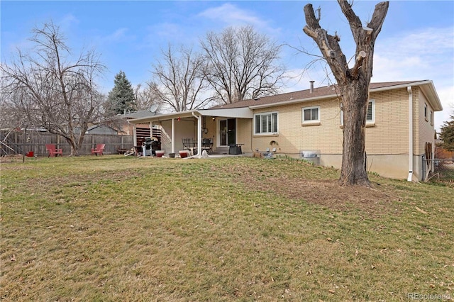 back of house with a yard, brick siding, and a fenced backyard