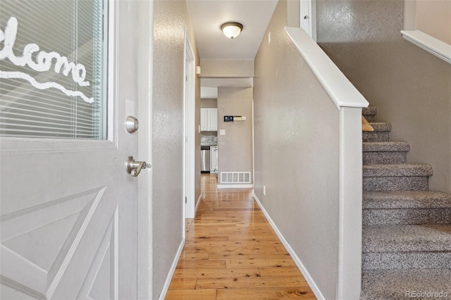 7667 W Brook Dr, Littleton, CO 80128 - hallway featuring light wood finished floors, stairs, and a textured wall