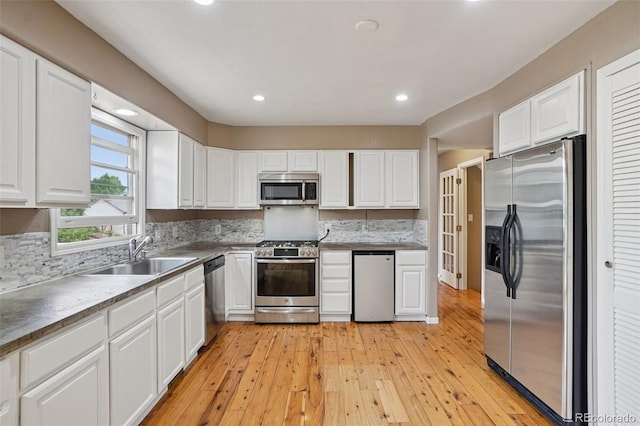 7667 W Brook Dr, Littleton, CO 80128 - kitchen featuring stainless steel appliances, white cabinetry, tasteful backsplash, light wood-type flooring, and recessed lighting