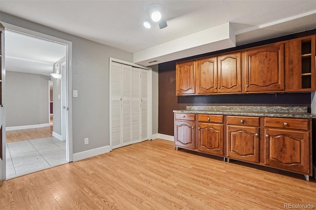 7667 W Brook Dr, Littleton, CO 80128 - kitchen with brown cabinets, light wood-style floors, open shelves, and dark stone countertops