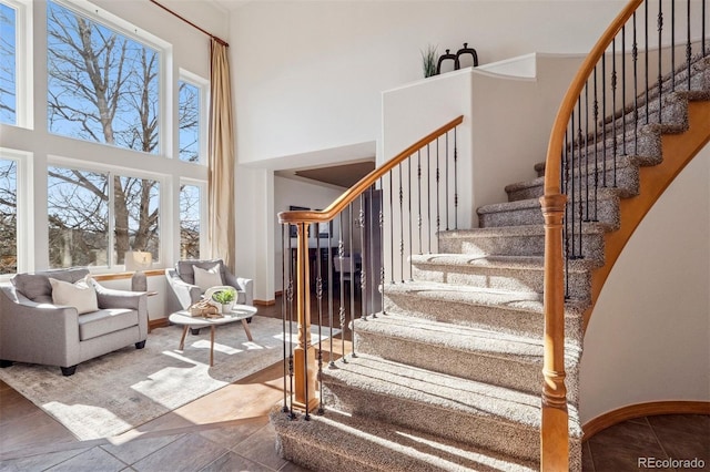 stairway with a high ceiling, tile patterned flooring, and baseboards