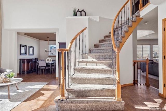 stairs featuring a notable chandelier, a towering ceiling, and baseboards