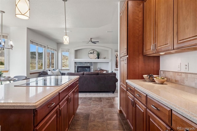 kitchen with a ceiling fan, pendant lighting, a tiled fireplace, and black electric stovetop