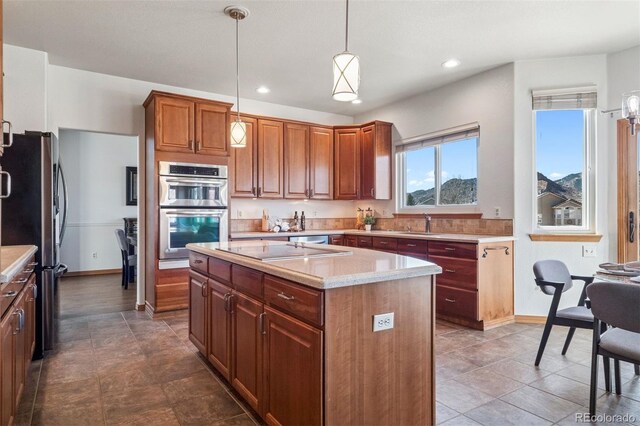 kitchen with stainless steel appliances, recessed lighting, hanging light fixtures, a kitchen island, and baseboards