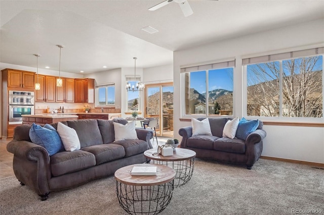 living area with baseboards, ceiling fan with notable chandelier, recessed lighting, and a healthy amount of sunlight