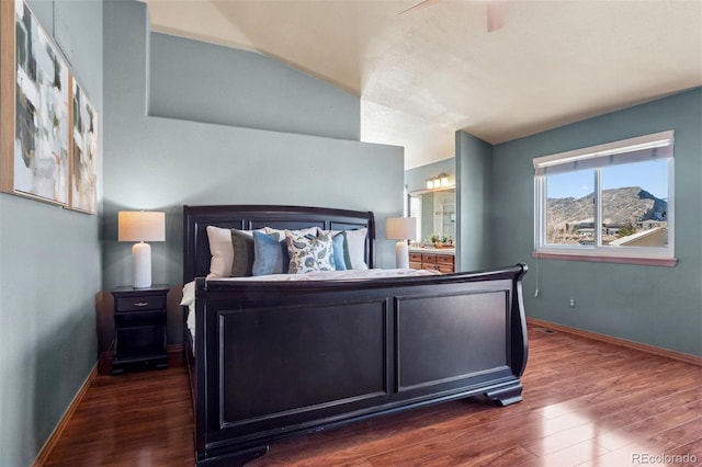 bedroom featuring lofted ceiling, ensuite bathroom, wood finished floors, and baseboards