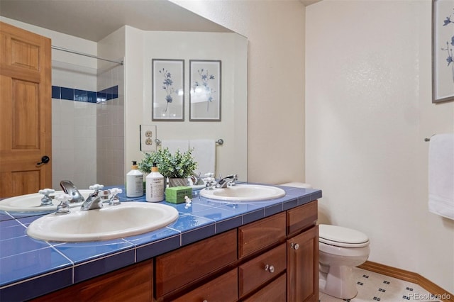 bathroom featuring toilet, double vanity, baseboards, and a sink