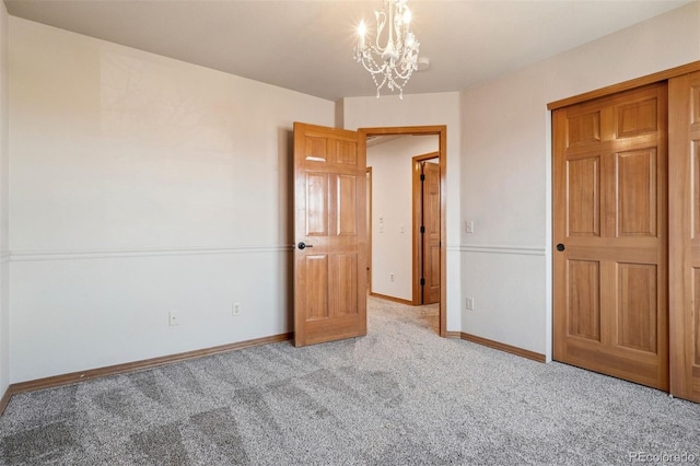 interior space featuring baseboards, a chandelier, and carpet flooring