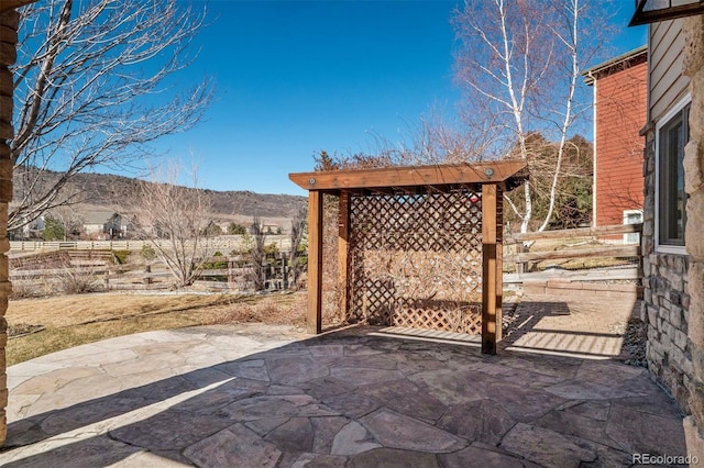 view of patio with fence and a mountain view