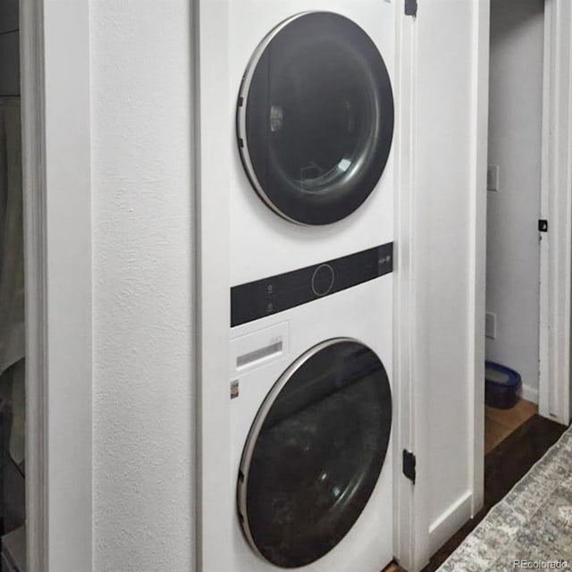 washroom featuring hardwood / wood-style floors and stacked washing maching and dryer