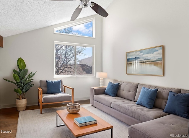 living area featuring a ceiling fan, a textured ceiling, wood finished floors, baseboards, and vaulted ceiling