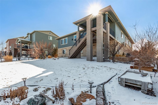 snow covered property with stairway