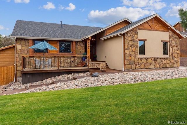 back of house with stone siding, a yard, and a shingled roof