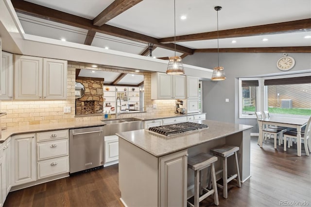 kitchen with appliances with stainless steel finishes, a sink, decorative backsplash, a kitchen island, and dark wood finished floors