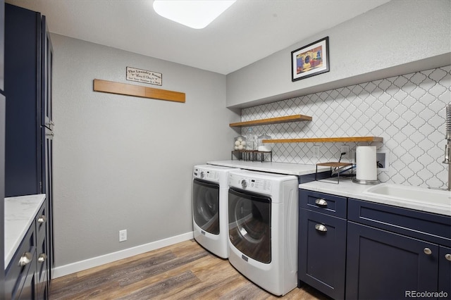laundry area featuring washer and clothes dryer, cabinet space, light wood finished floors, and baseboards