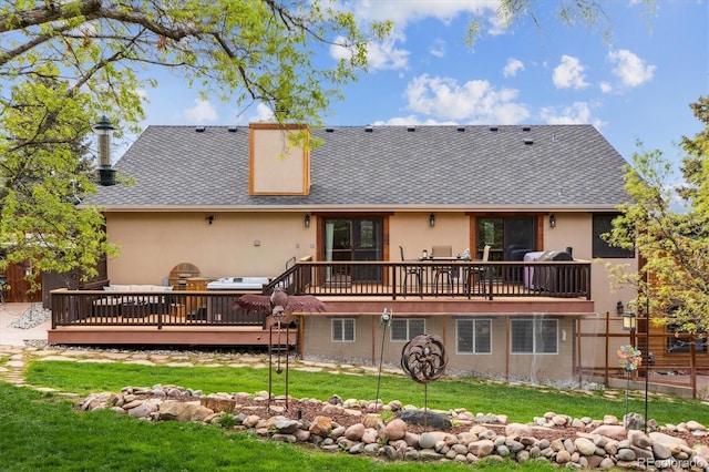 back of house with a deck, stucco siding, a lawn, and roof with shingles